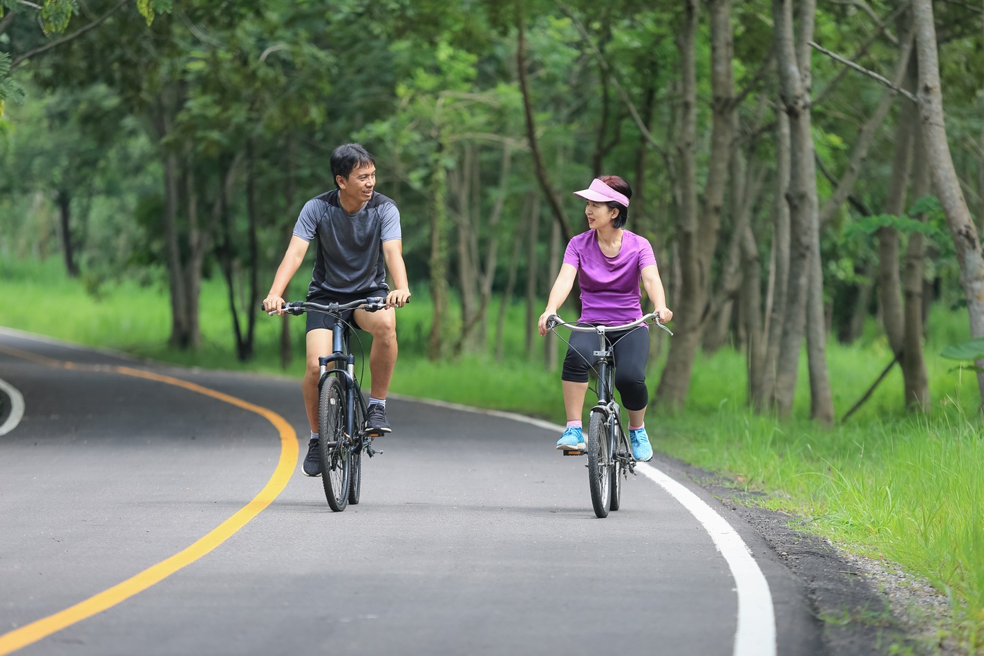 中年夫妻在公園騎自行車放鬆運動。